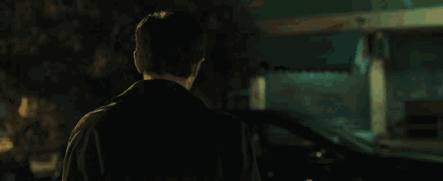 a man is standing in front of a car at night