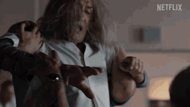 a man with long hair is being held in a room with a netflix logo on the bottom
