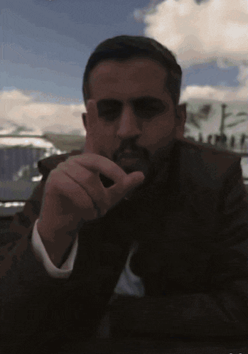 a man with a beard is pointing at the camera with his finger