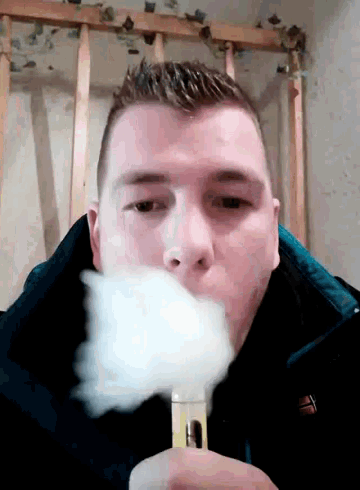 a man in a black jacket is blowing smoke out of a device