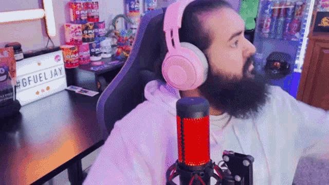 a man wearing pink headphones is sitting in front of a microphone