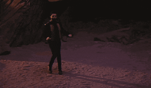 a man in a suit and tie stands in front of a rock formation