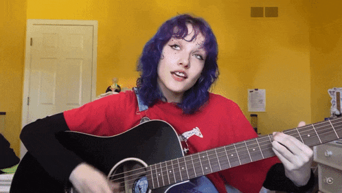 a girl with purple hair is playing an acoustic guitar in front of a yellow wall