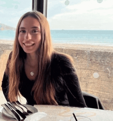 a woman sits at a table with a plate of food and a glass of water