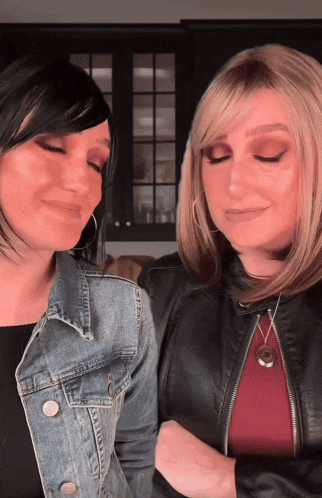 two women are standing next to each other with their eyes closed and one is wearing a necklace with the letter p on it