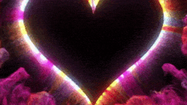 a colorful heart is surrounded by smoke and lights on a dark background .