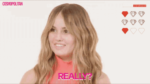 a woman with braces on her teeth is smiling in front of a scoreboard that says cosmopolitan