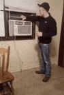 a man is standing in front of a window air conditioner in a living room .