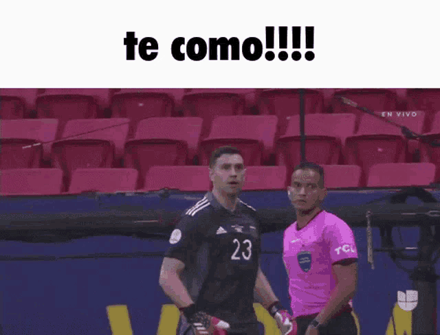 a soccer player with the number 23 on his jersey is standing next to a referee in a stadium .