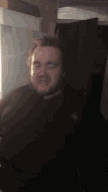 a blurry photo of a man with glasses and a black shirt