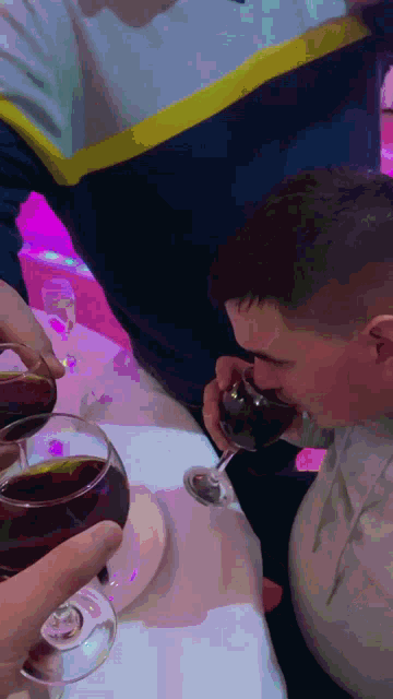 a man drinking a glass of wine while another man holds a glass