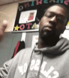 a man wearing a grey hoodie with the word ota on the front