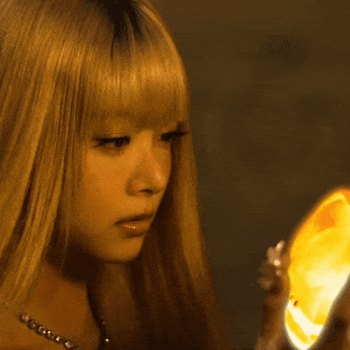 a woman with blonde hair is holding a glowing object