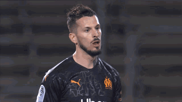a soccer player wearing a black jersey with puma on it