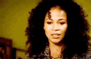 a close up of a woman 's face with curly hair .