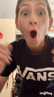 a boy wearing a black vans shirt is making a funny face
