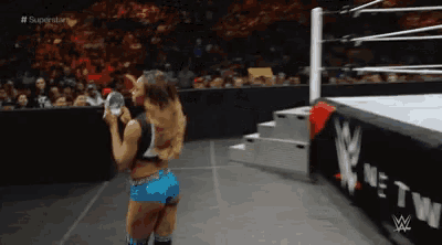 a woman in a wrestling ring holding a bottle of water