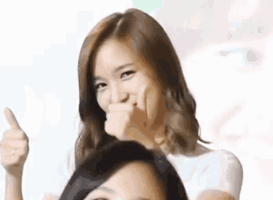 a woman is making a funny face while giving a thumbs up sign .
