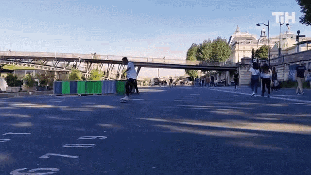 a man is riding a skateboard down a street with the letters th written on the side of the road