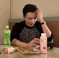 a man is sitting at a table with a bag of food and a bottle of strawberry juice .