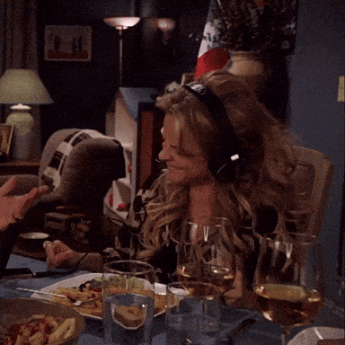 a woman wearing headphones sitting at a table with wine glasses