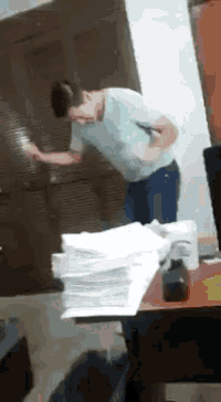 a man in a blue shirt is standing in front of a stack of papers .
