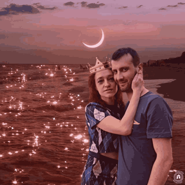 a man and a woman are posing for a picture on a beach with a crescent moon in the background