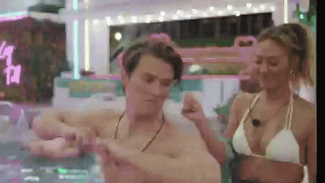 a man and a woman are standing next to each other in a pool .