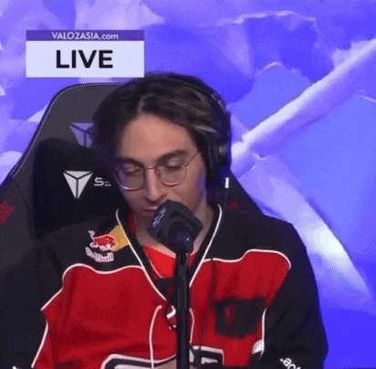 a man in a red and black jersey is sitting in front of a microphone .