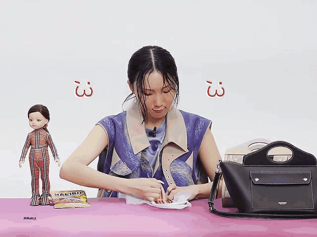 a woman sitting at a table with a bag that says burberry on the front