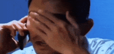 a man is crying while talking on a cell phone .