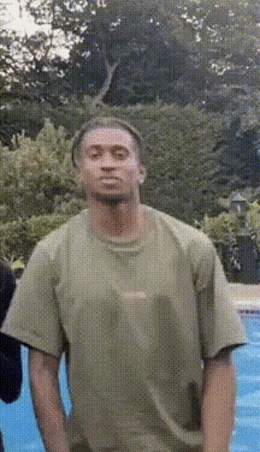 a man in a green shirt is standing in front of a swimming pool