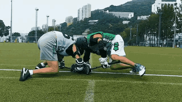 a lacrosse player with the number 8 on his shorts is kneeling down on the field