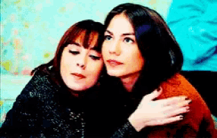 two women are sitting next to each other and hugging .