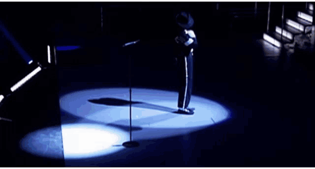 a man is standing in front of a microphone in a dark room