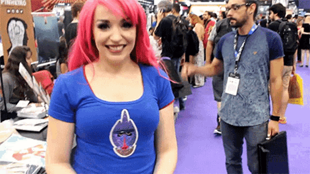 a woman with pink hair is wearing a blue shirt