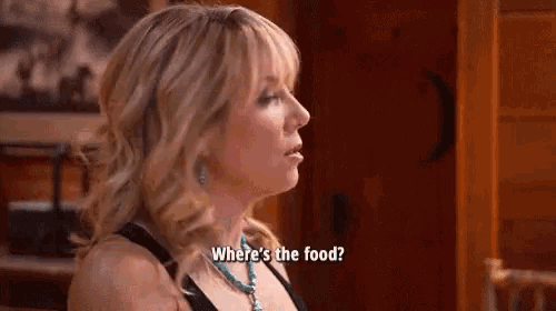 a woman is sitting at a table and asking where 's the food ?