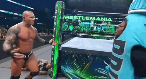 a wrestling match is taking place in front of a sign that says restlemania .