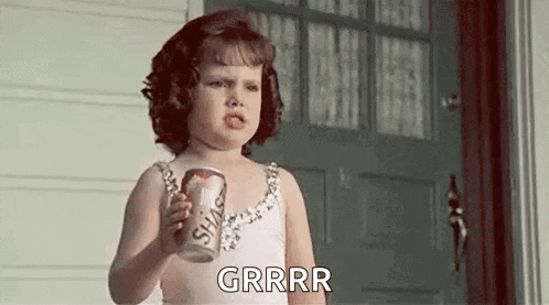 a little girl is holding a can of soda in her hand .