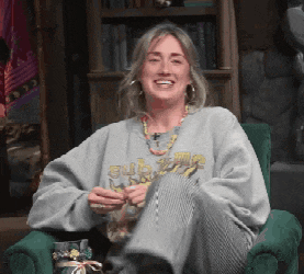 a woman is sitting in a chair wearing a sweatshirt that says ' submariner ' on it