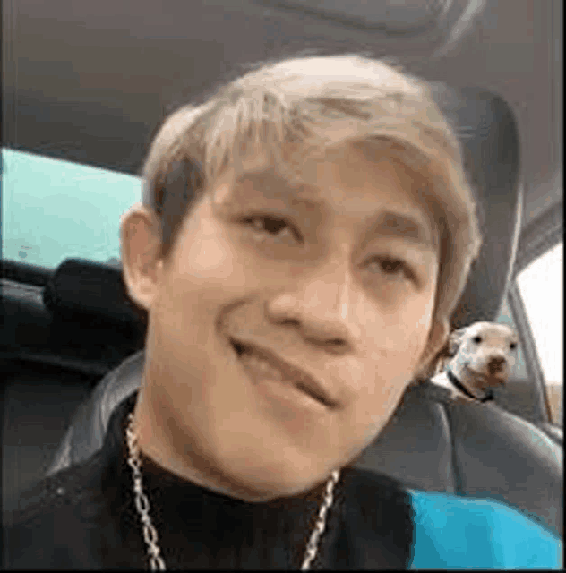 a man is sitting in the back seat of a car with a dog in his lap .