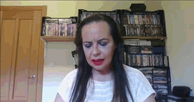 a woman wearing headphones and red lipstick stands in front of a bookshelf full of dvds