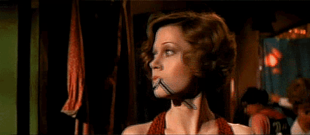 a woman with a cigarette in her mouth looks at the camera