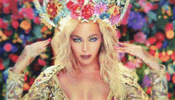 a woman wearing a flower crown is standing in front of a bunch of flowers .