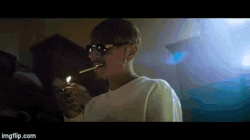a man is smoking a cigarette in a dark room with a lighter .