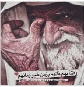 an older man with a beard is covering his eyes with his hand .