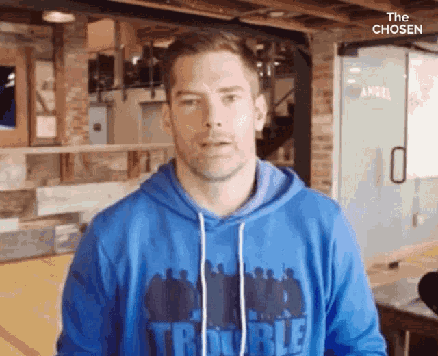 a man is wearing a blue hoodie that says trouble on it