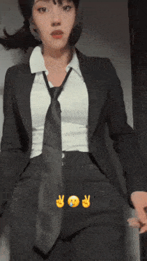 a woman in a suit and tie is standing in front of a wall with emojis on it