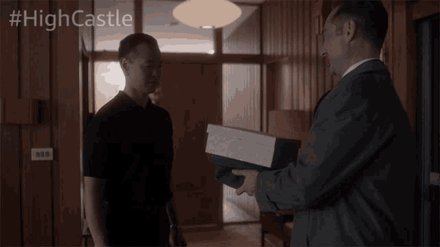 a man holding a box in front of a sign that says highcastle