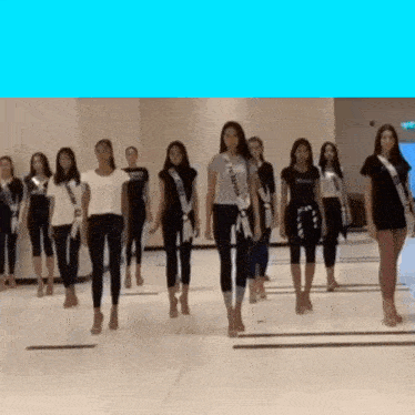 a group of women are walking in a line and one of them is wearing a sash that says ' miss china ' on it